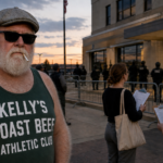 Dick Bulger, expressionless and wearing opaque sunglasses and a dark green Kellys Roast Beef Athletic Club tank top, outside an immigration enforcement building